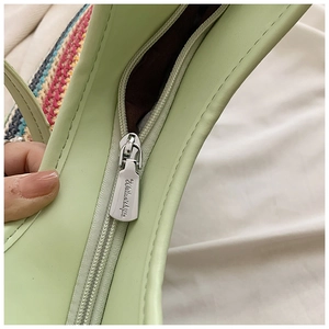 Detail of silver metal zipper closure on light green woven tote bag with brown lining
