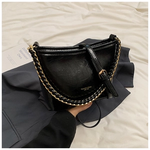 Close-up of black cracked leather shoulder bag with gold chain and strap details