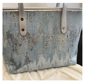 Detailed macro view of sequined denim tote bag with silver leather handles and metallic trim