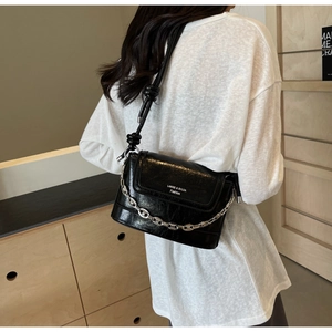 Detail of black faux leather bucket bag with silver chain and embossed fashion text