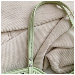 Close-up of mint green faux leather strap with silver rivets and neat stitching details