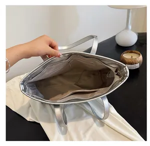Interior view of large silver tote bag showing zipper pockets and spacious capacity