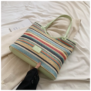 Detail of colorful woven tote bag featuring light green leather handles and metal rivets