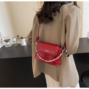 Detail of red patent leather bucket bag with silver chain strap and flap closure