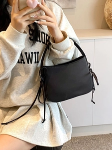 Sac fourre-tout noir minimaliste avec pompons porté par un mannequin pour un style décontracté