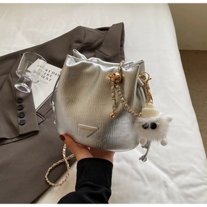 Detail of silver bucket bag with gold chain and cute white monster plush charm