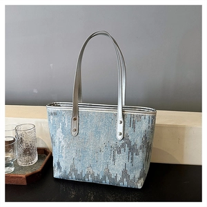 Close-up of blue denim tote bag with silver sequins and metallic shoulder straps