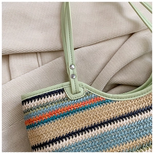 Detail of colorful woven tote bag featuring wavy stripes and light green leather handles