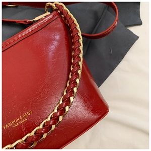 Detail of red leather bag with gold chain strap and embossed fashion brand lettering