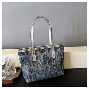 Detail of blue-grey sequined fabric texture and metallic silver handles on a tote bag