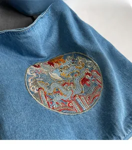 Detail of premium denim tote with intricate dragon embroidery and soft fabric texture