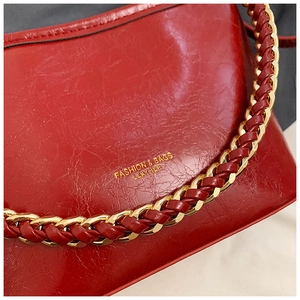 Detail of red oil wax leather shoulder bag with golden chain and fashion logo