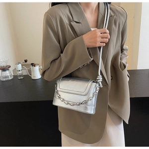 Detail of silver metallic bucket bag with cracked texture and chain accent on shoulder