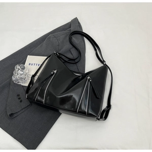 Close-up of glossy black tote bag with dual silver zipper details on suit jacket