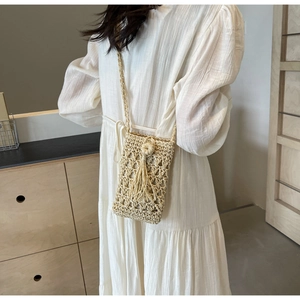 Detail view of woven phone bag with hollow patterns and decorative fringe tassel