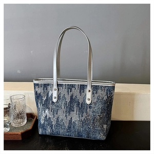 Detailed view of large tote bag with blue geometric textured fabric and silver handles