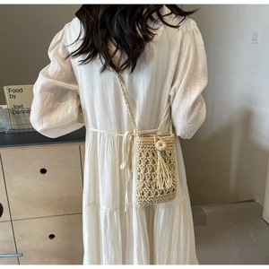 Close-up of beige crochet cell phone bag with floral applique and fringe details
