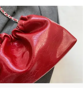 Détail du sac seau rouge brillant avec cuir texturé plissé et chaîne en métal argenté