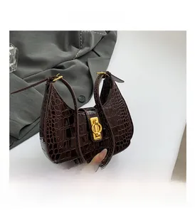 Détail d'un sac hobo marron foncé à effet croco avec boucle dorée et fini brillant
