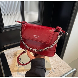 Macro shot of dark red oil wax leather handbag with silver chain and logo detail