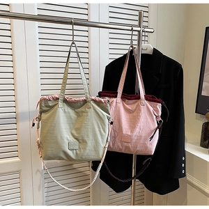 Detail of drawstring canvas tote with woven shoulder strap and contrast color panels