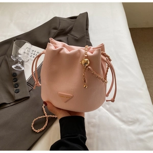 Detailed macro view of pink pleated bucket bag with gold chain and triangle logo