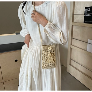 Close-up of handmade woven straw bag with tassel detail and bohemian mesh texture