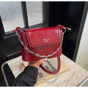 Detail view of red glossy wrinkled leather bucket bag with silver chain and knot hardware