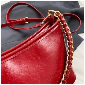 Detail of red oil wax leather shoulder bag with golden chain handle and texture