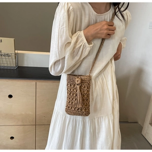 Detailed shot of handmade woven straw bag featuring hollow mesh and tassel accents