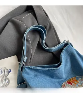 Detail of adjustable denim shoulder strap with silver metal rings on a tote bag