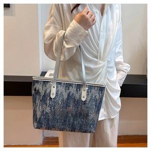 Detailed view of large navy denim tote bag with shimmering gradient sequin patterns