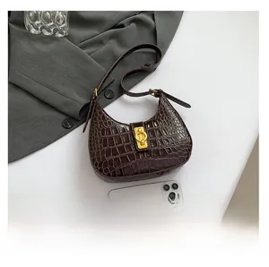 Détail du sac sous le bras marron foncé motif crocodile avec fermoir doré et référence
