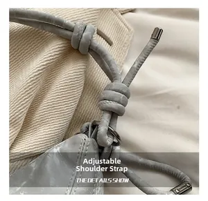 Detail showing adjustable shoulder strap with knot and metal ring on grey crossbody bag