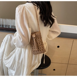 Detail of hand-woven straw crossbody bag with decorative tassels and intricate net pattern