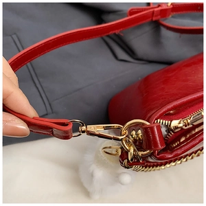 Detail of red synthetic leather texture with gold zipper and chain strap connectors