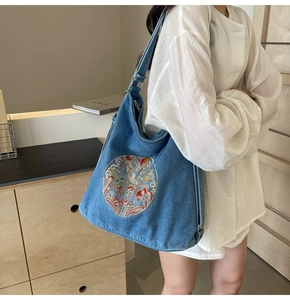 Detailed close-up of blue denim hobo bag with colorful traditional circular embroidery