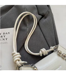 Close-up of white leather shoulder bag with knotted strap and silver bead detail