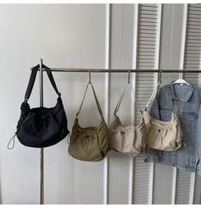 Nylon crescent crossbody bags with drawstring folds in black, green, beige, and cream colors