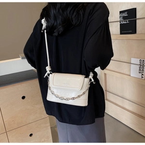 Detail view of cream PU crossbody bag with white knotted strap and silver chain link