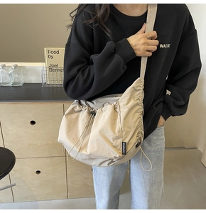 Detail of beige nylon crossbody bag featuring pleated design and drawstring closure