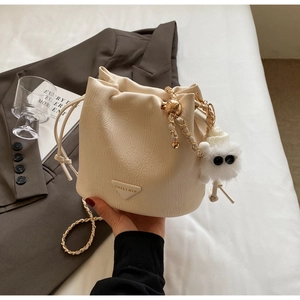 Detail of white drawstring bucket bag with leaf texture and plush monster charm