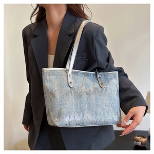 Detail of light blue sequined tote bag with white leather straps worn by a model
