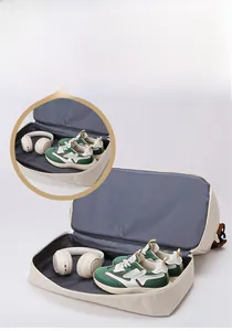 Détail du sac de voyage montrant le compartiment chaussures et des écouteurs