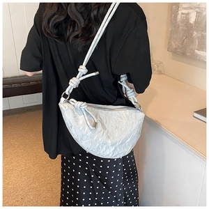 Detailed shot of silver textured crescent crossbody bag with thick knotted shoulder strap