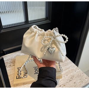 Détail du nœud en perles et pendentif cœur argenté sur le sac seau blanc chic