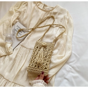 Detail of hand-woven straw crossbody bag with elegant fringe and hollow weave texture