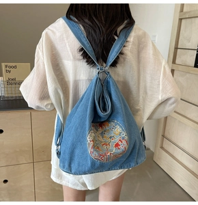 Blue denim backpack featuring intricate colorful dragon embroidery and drawstring closure