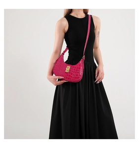 Modèle portant un sac demi-lune magenta à motif crocodile avec boucle dorée et bandoulière