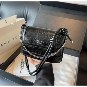 Detail of black glossy wrinkled bucket bag with silver chain and knotted strap design